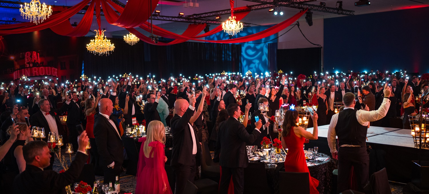 Photo of ballroom full of people holding lit flashlights