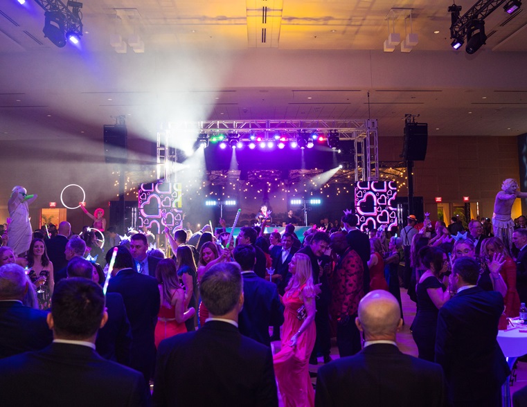 Photo of crowded dance floor with circus-type performers on podiums