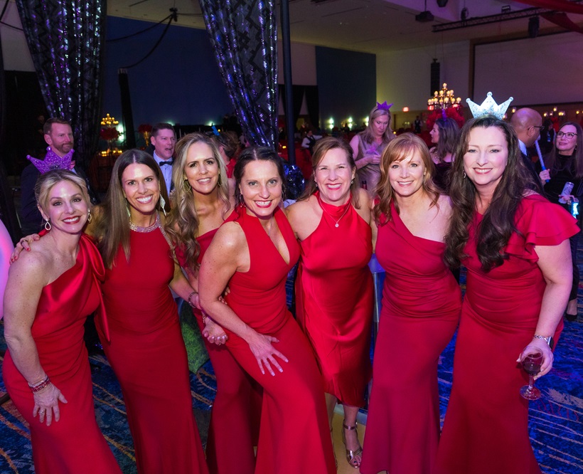 Photo of group of seven women all wearing red dresses